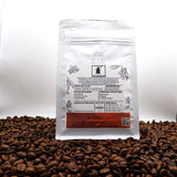 Coffee bag with a label on a bed of coffee beans against a white background